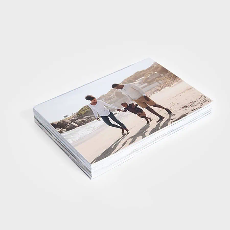 Fotoclube com caixas de fotos na praia, mostrando momentos familiares ao pôr do sol.