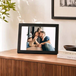 Passepartout preto com fotografia de família, apresentado sobre um móvel de madeira.